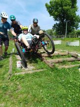 Une cycliste franchit un obstacle important de côté avec deux parades